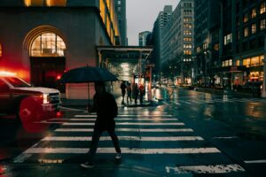 A person crosses a wet street in the city.